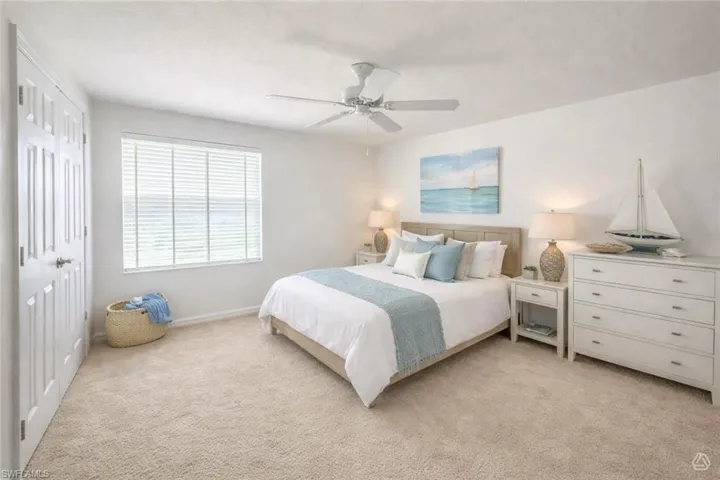Bedroom featuring neutral-toned carpet flooring, a window with horizontal blinds, a ceiling fan, and a paneled door