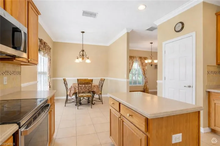 Kitchen featuring wood cabinetry, light countertops, stainless steel appliances, and tile flooring