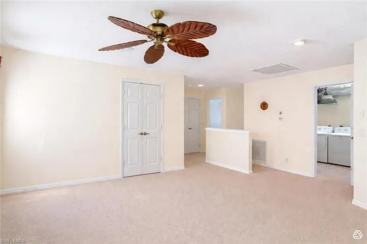 Carpeted room with a ceiling fan featuring palm-leaf style blades