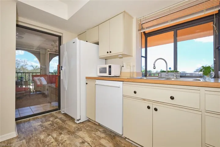 Kitchen with cream cabinets, white appliances, and light wood-type flooring