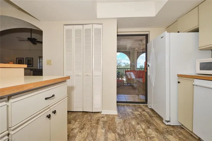 Kitchen with light countertops, cream cabinetry, white appliances, and dark wood finished floors