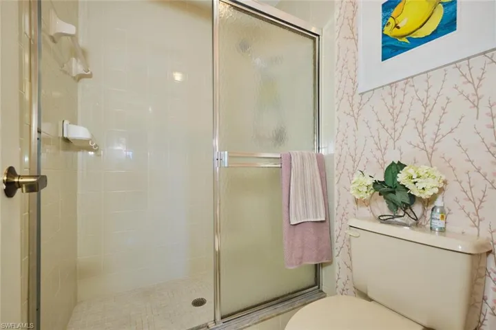 Bathroom with a stall shower and wallpapered walls