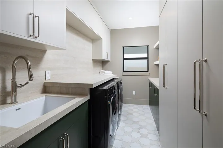 Clothes washing area with sink, cabinets, and independent washer and dryer