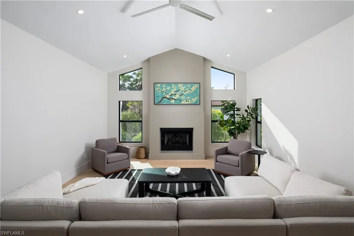 Living room with ceiling fan, high vaulted ceiling, and wood-type flooring