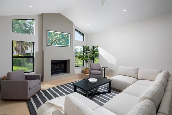 Living room featuring plenty of natural light, high vaulted ceiling, and light wood-type flooring