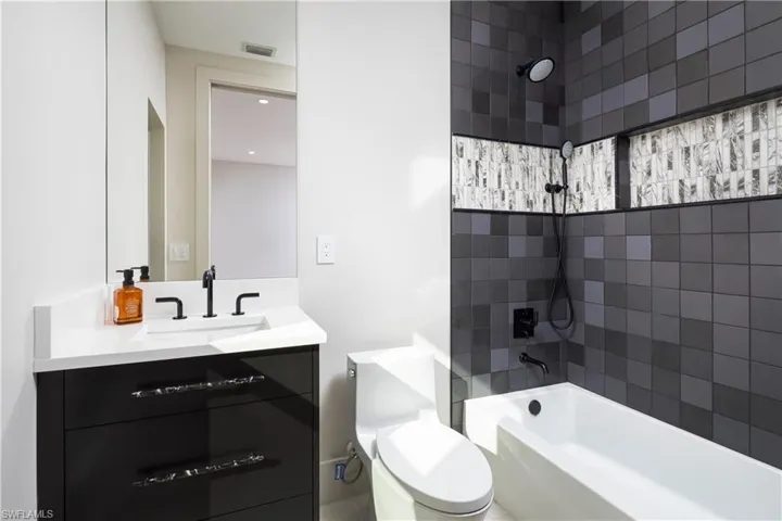 Full bathroom featuring vanity, tiled shower / bath combo, and toilet