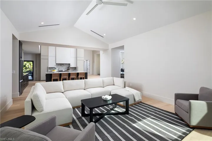 Living room with light hardwood / wood-style floors, ceiling fan, and lofted ceiling