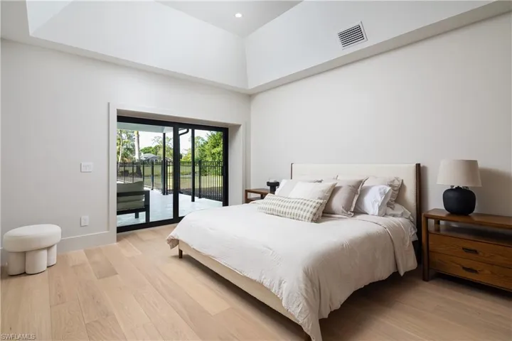 Bedroom featuring access to exterior, light wood-type flooring, and a towering ceiling