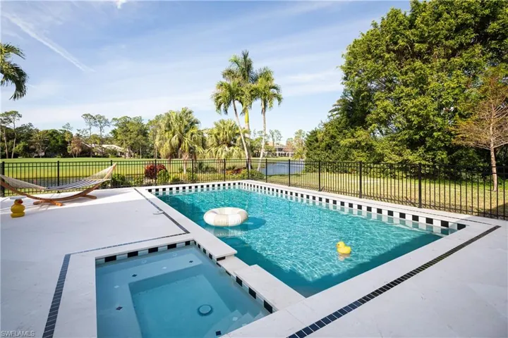 View of swimming pool with a water view and an in ground hot tub