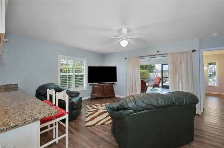 Living room with ceiling fan, plenty of natural light, and dark hardwood / wood-style floors