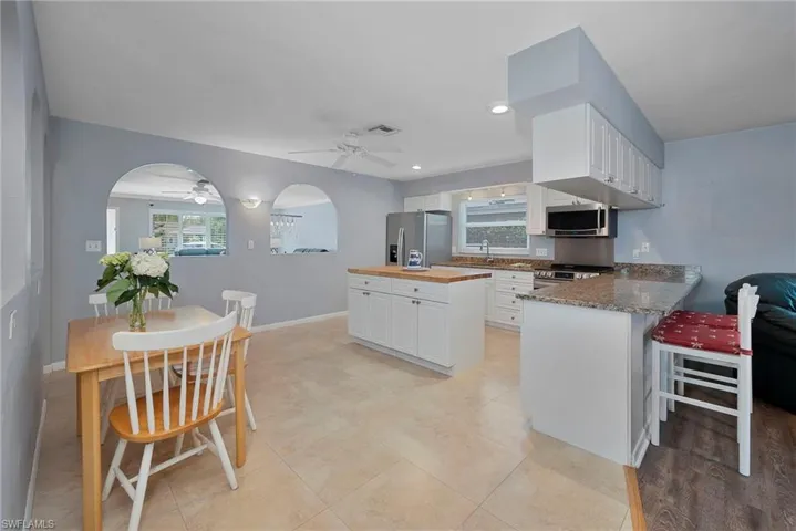 Kitchen with white cabinets, appliances with stainless steel finishes, kitchen peninsula, and butcher block counters