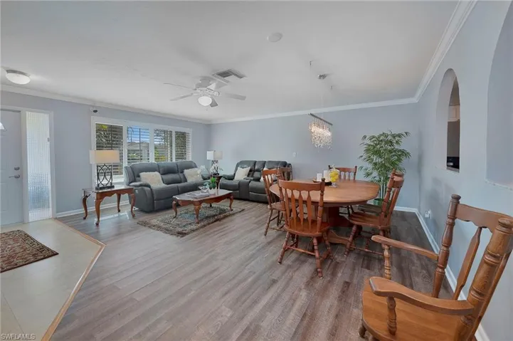 Dining space with hardwood / wood-style floors, ceiling fan with notable chandelier, and ornamental molding