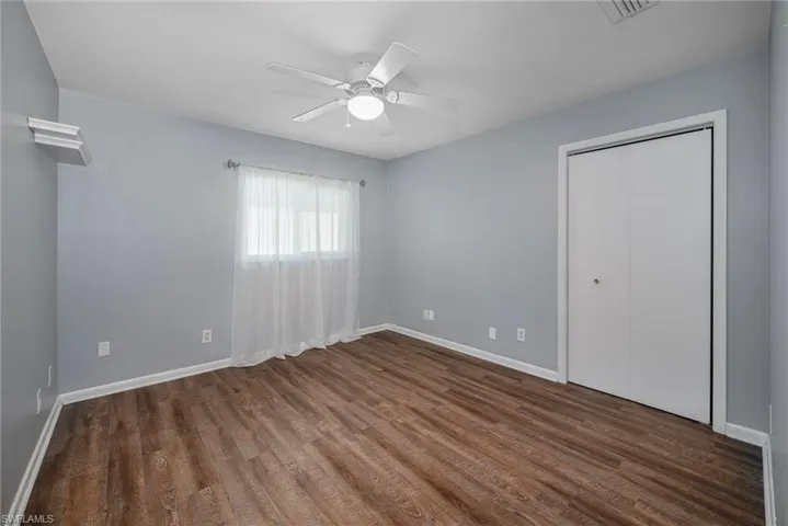 Unfurnished bedroom featuring a closet, ceiling fan, and dark wood-type flooring