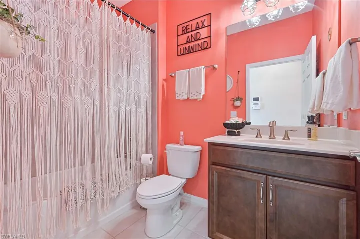 Bathroom featuring vanity, light tile patterned floors, and shower / tub combo with curtain