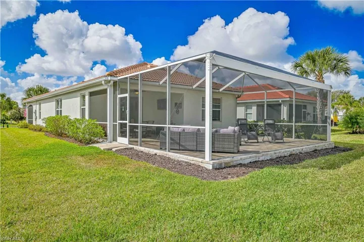 Rear view of property with outdoor seating, a lanai, a yard, and a sunroom