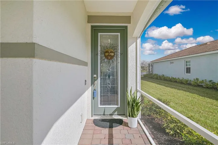 View of exterior entry featuring stucco siding and a lawn