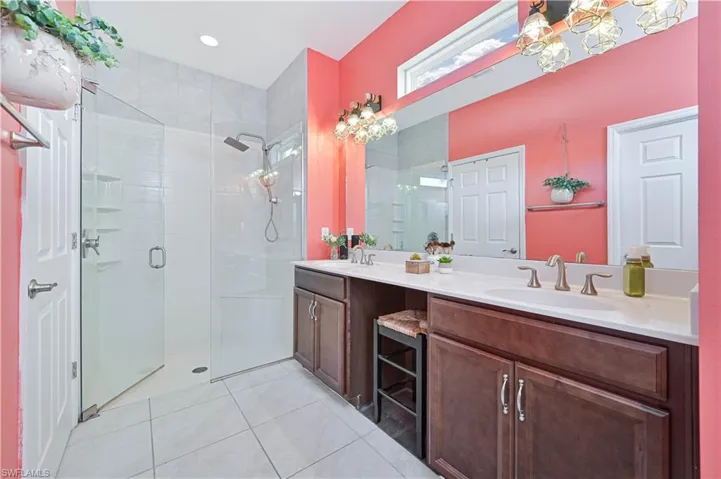 Bathroom with a stall shower, double vanity, and light tile patterned floors