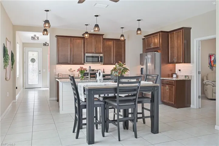 Kitchen with a ceiling fan, light stone counters, tasteful backsplash, and stainless steel appliances