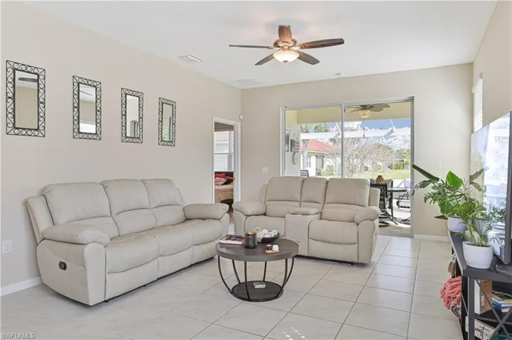 Living room with a ceiling fan and light tile patterned floors