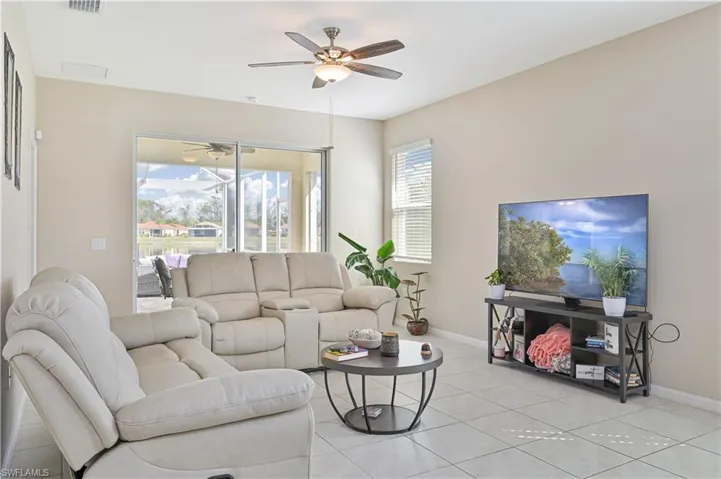 Living room with a ceiling fan and light tile patterned floors