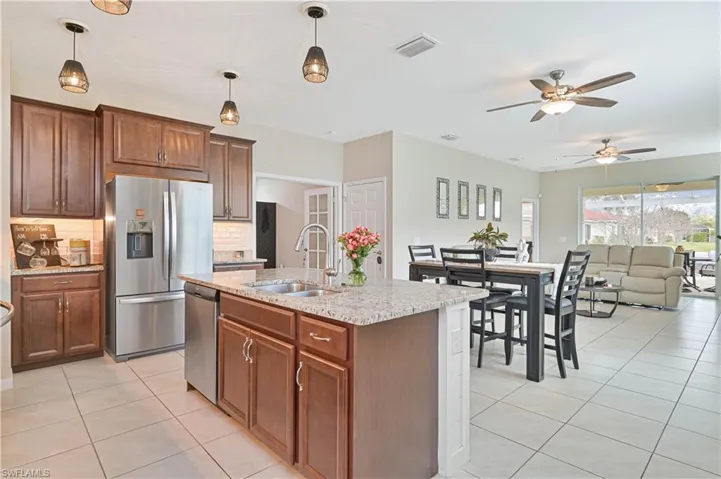 Kitchen featuring stainless steel appliances, light stone countertops, tasteful backsplash, light tile patterned flooring, and ceiling fan