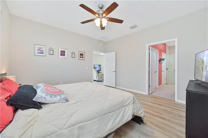 Bedroom featuring light wood-style flooring, ceiling fan, and ensuite bath
