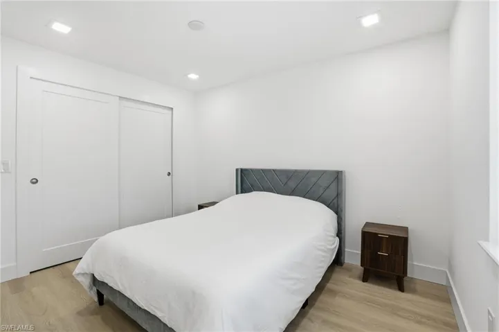 Recessed lighting illuminates this room, featuring light wood-finish flooring and a white color palette