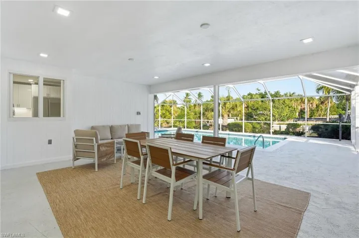 Spacious screened patio featuring an in-ground swimming pool, white shiplap wall paneling, and an adjacent interior window