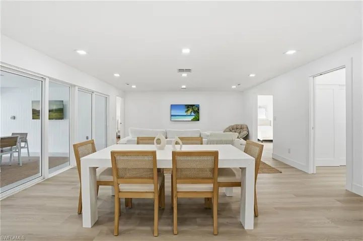 Open-concept dining and living area featuring light wood-finish flooring and white walls