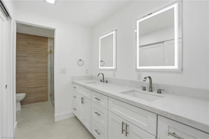 Double vanity with white cabinetry, integrated sinks, and polished countertops