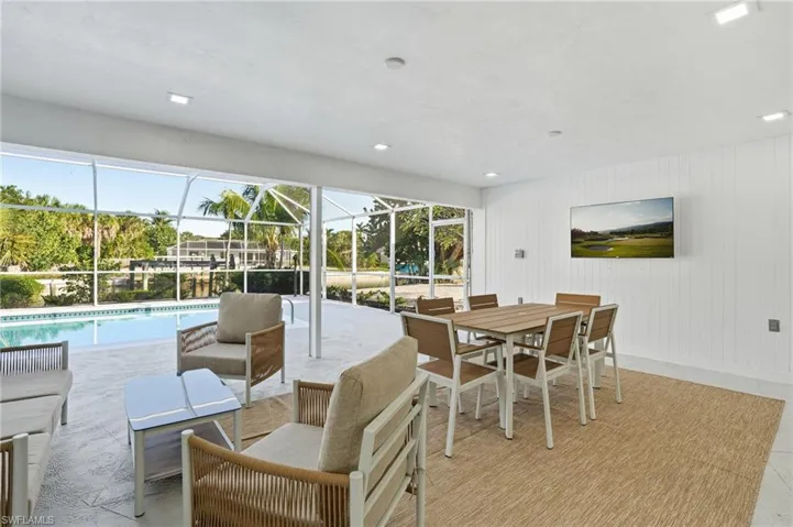 Expansive screened lanai featuring a swimming pool, textured flooring, and a shiplap accent wall
