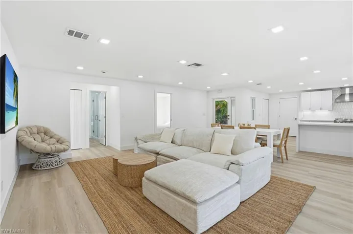 Open-concept living space featuring wood-finish flooring, recessed lighting, and white walls