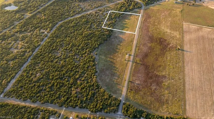Expansive land parcel featuring partial tree coverage, open grassy areas, and a defined property boundary