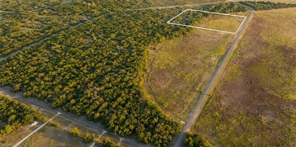 Expansive undeveloped land featuring a cleared parcel, extensive tree cover, and bordering roadways