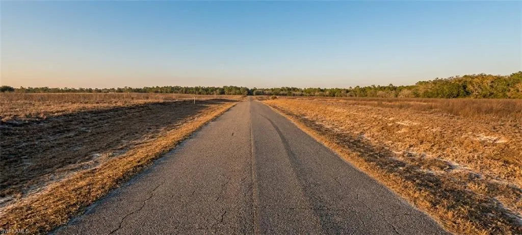Paved road extending through open, undeveloped land