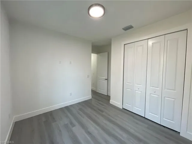 Unfurnished bedroom with baseboards, dark wood-type flooring, and a closet