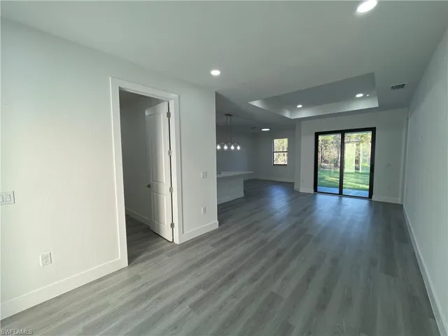Spare room with recessed lighting, baseboards, a raised ceiling, and wood finished floors