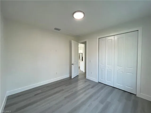 Unfurnished bedroom featuring wood finished floors, baseboards, and a closet