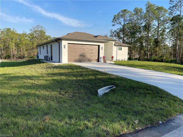 View of home's exterior with concrete driveway, stucco siding, a garage, and a lawn