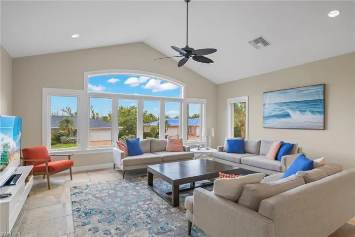 Living room featuring ceiling fan, light tile patterned floors, and high vaulted ceiling