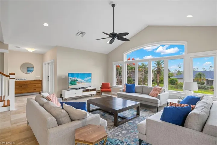 Tiled living room featuring lofted ceiling and ceiling fan