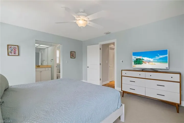 Carpeted bedroom featuring ensuite bath and ceiling fan