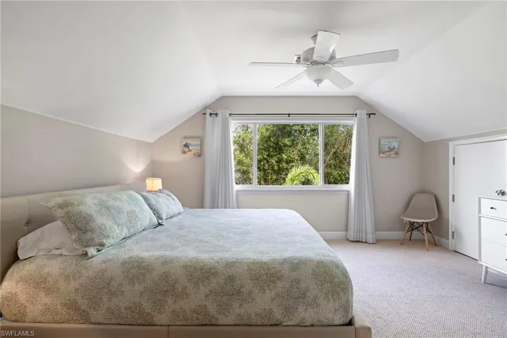 Carpeted bedroom with ceiling fan and vaulted ceiling