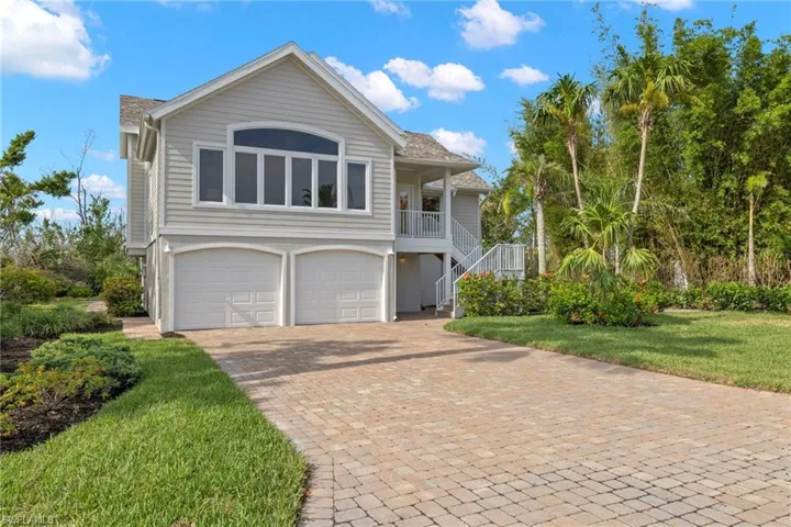 View of property with a front lawn, a garage, and covered porch