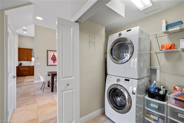 Laundry area with stacked washer and dryer and light tile patterned floors