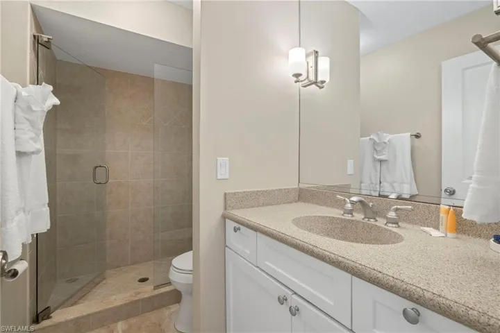 Bathroom featuring vanity, toilet, an enclosed shower, and tile patterned floors