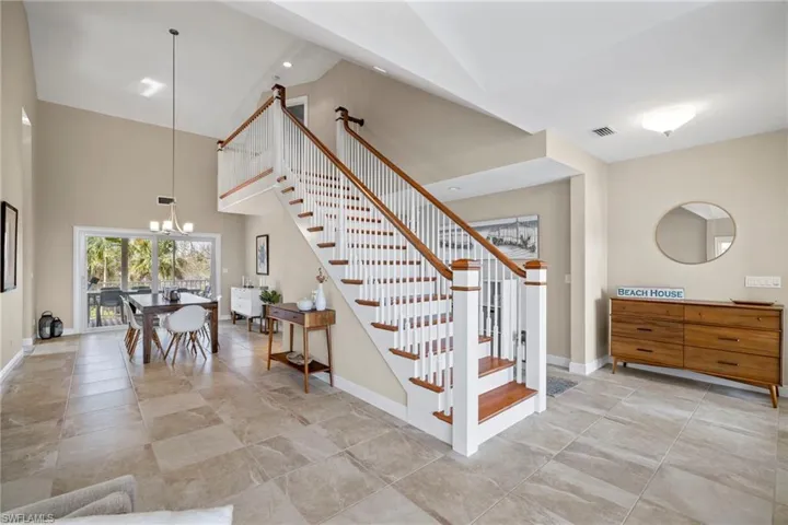 Staircase featuring a chandelier and high vaulted ceiling