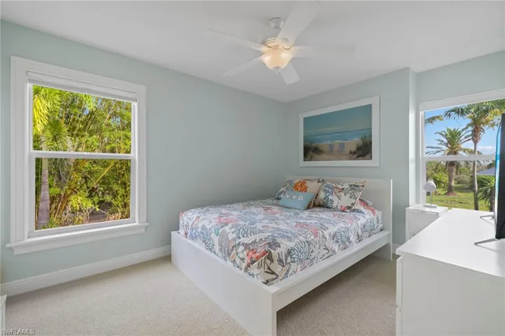 Carpeted bedroom with multiple windows and ceiling fan