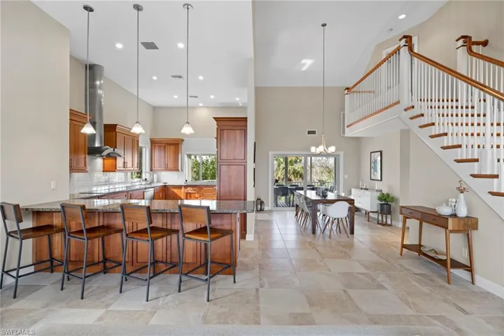 Kitchen with pendant lighting, wall chimney exhaust hood, a chandelier, and kitchen peninsula