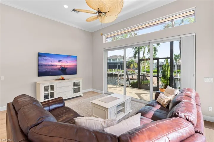 Living room featuring crown molding, light hardwood / wood-style floors, ceiling fan, and plenty of natural light